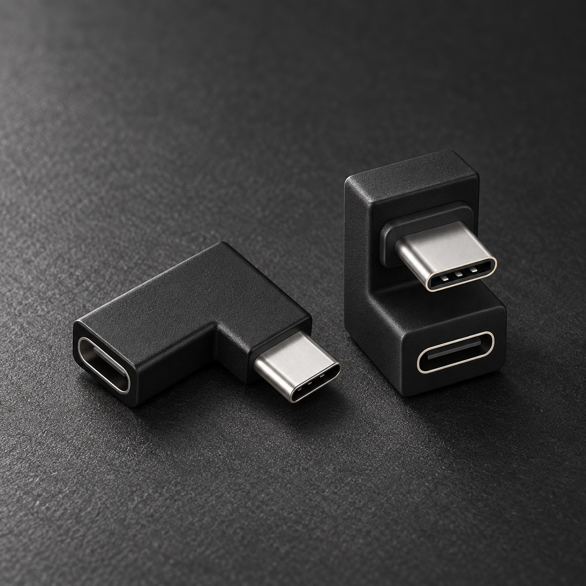 Black 90 degree and 180 degree USB-C adapters on dark graphite surface