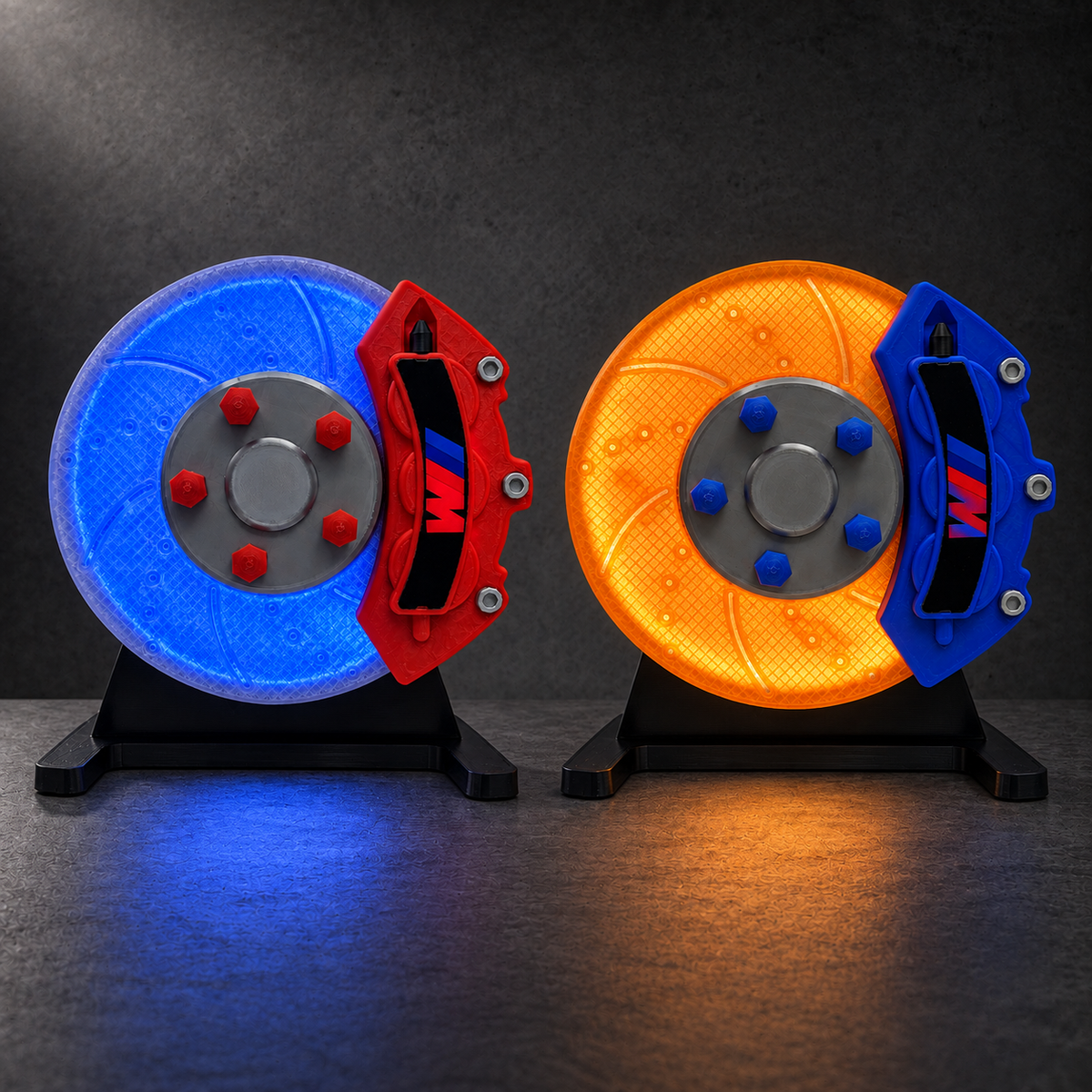 NOXLUX RGB and amber brake disc lamps on black desktop stands