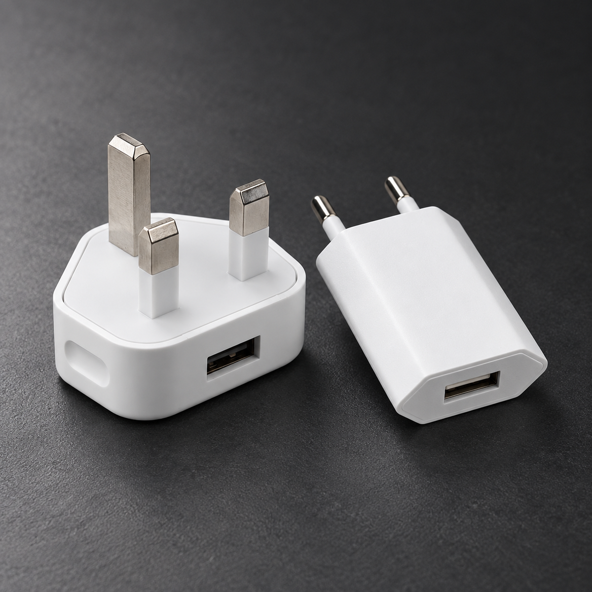 White UK and EU USB-A power plugs on dark graphite surface
